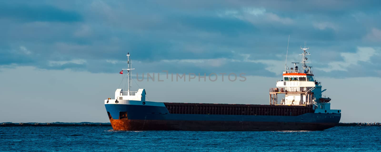 Blue bulk carrier sailing in still water