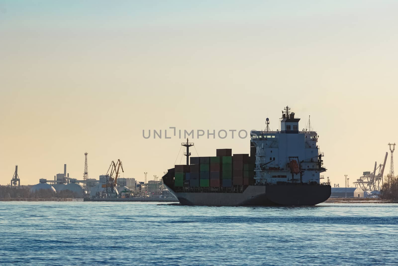 Modern grey container ship moving in still water