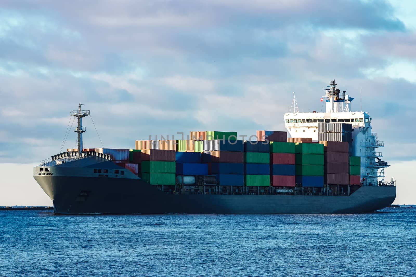 Modern grey container ship moving in still water