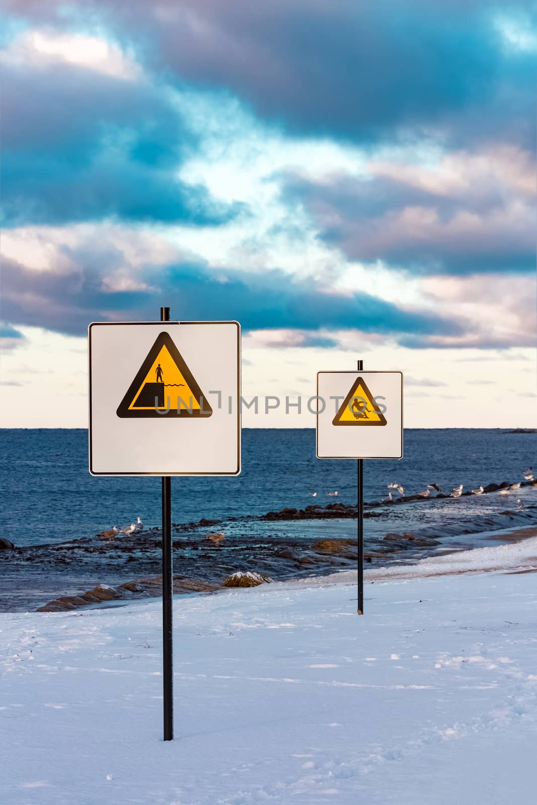 Two yellow warning signs on the winter beach