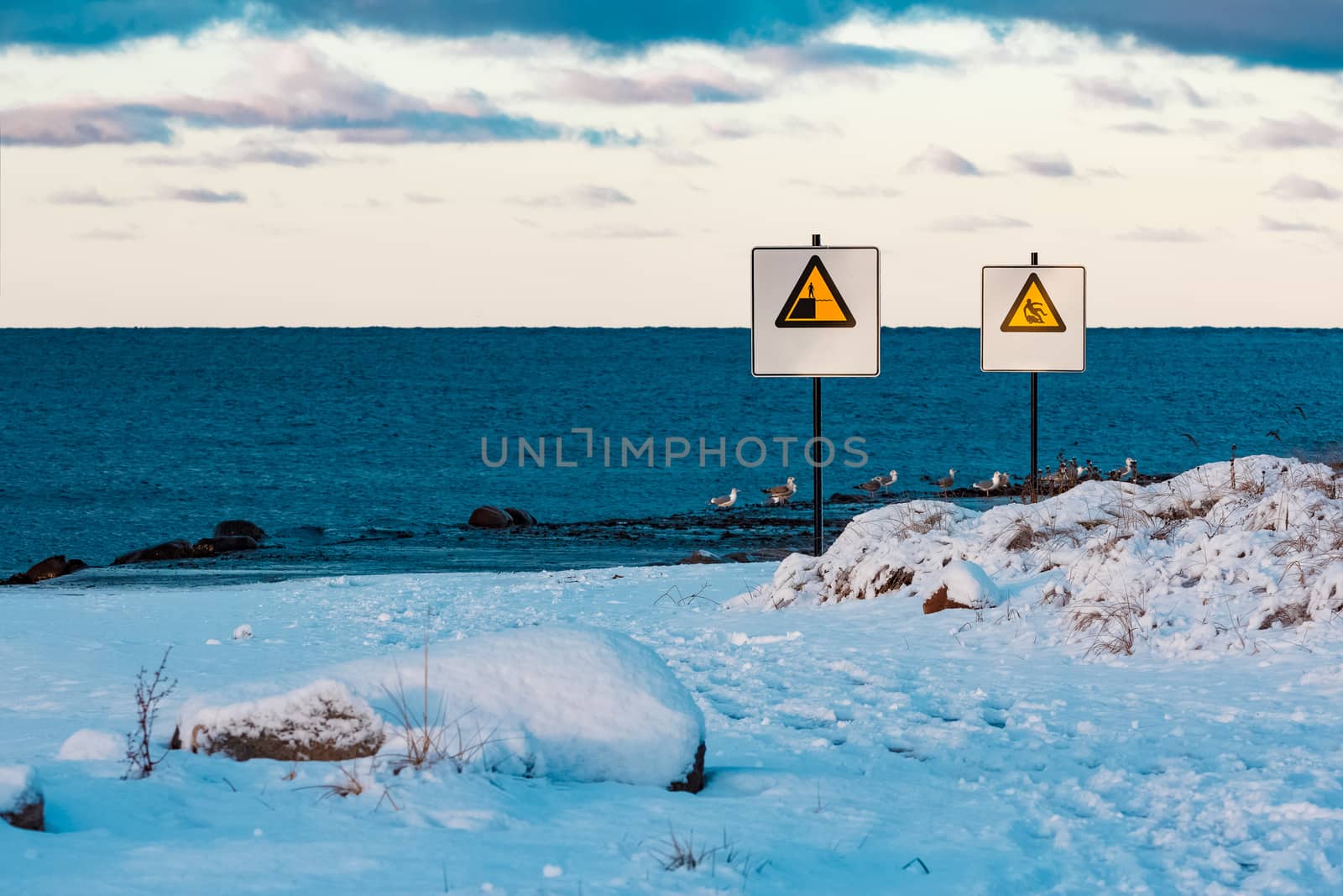 Two yellow warning signs on the winter beach