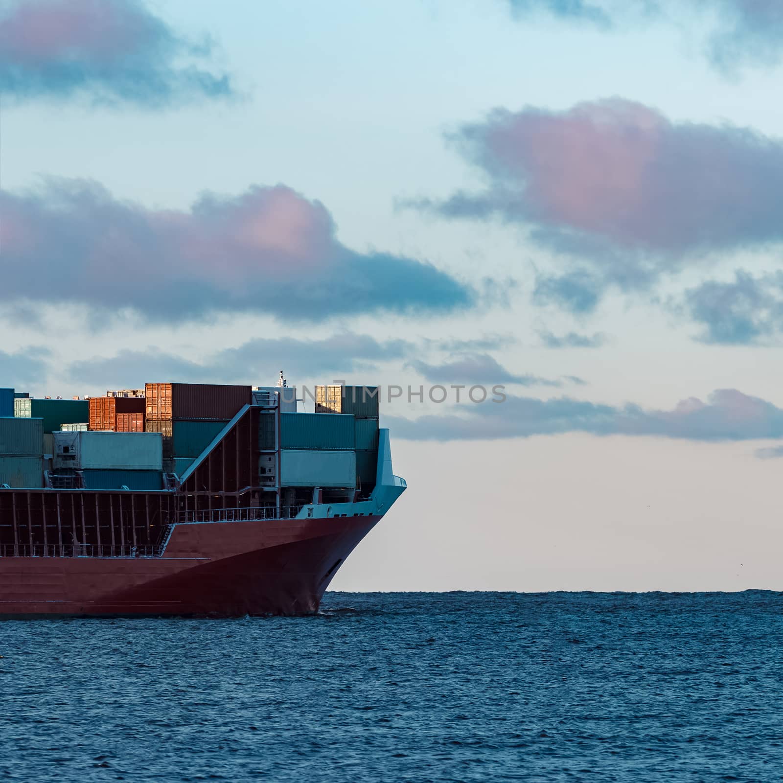 Full red container ship moving in still water