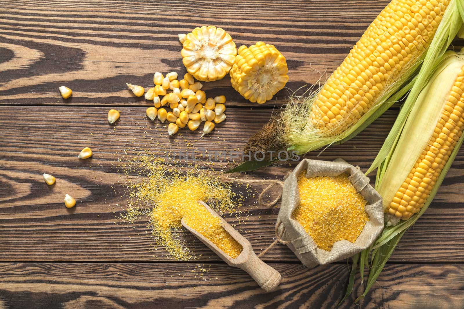 Fresh corn on cobs on rustic wooden table, top view. Dark wooden background freshly harvested organic corn. Corn grits in cloth sack.