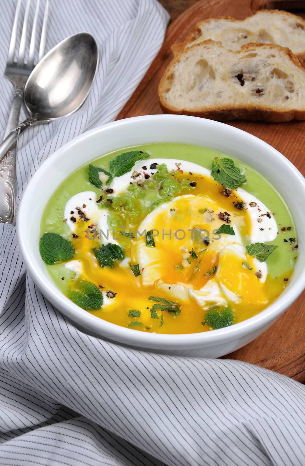 Pea puree soup with poached egg, sour cream, mint leaves seasoned with spices.
