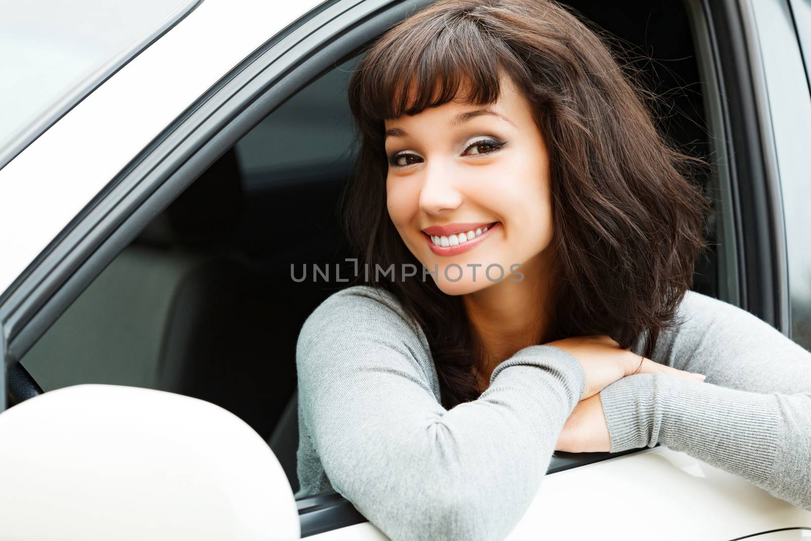 Pretty woman driver smiling to you from the white car