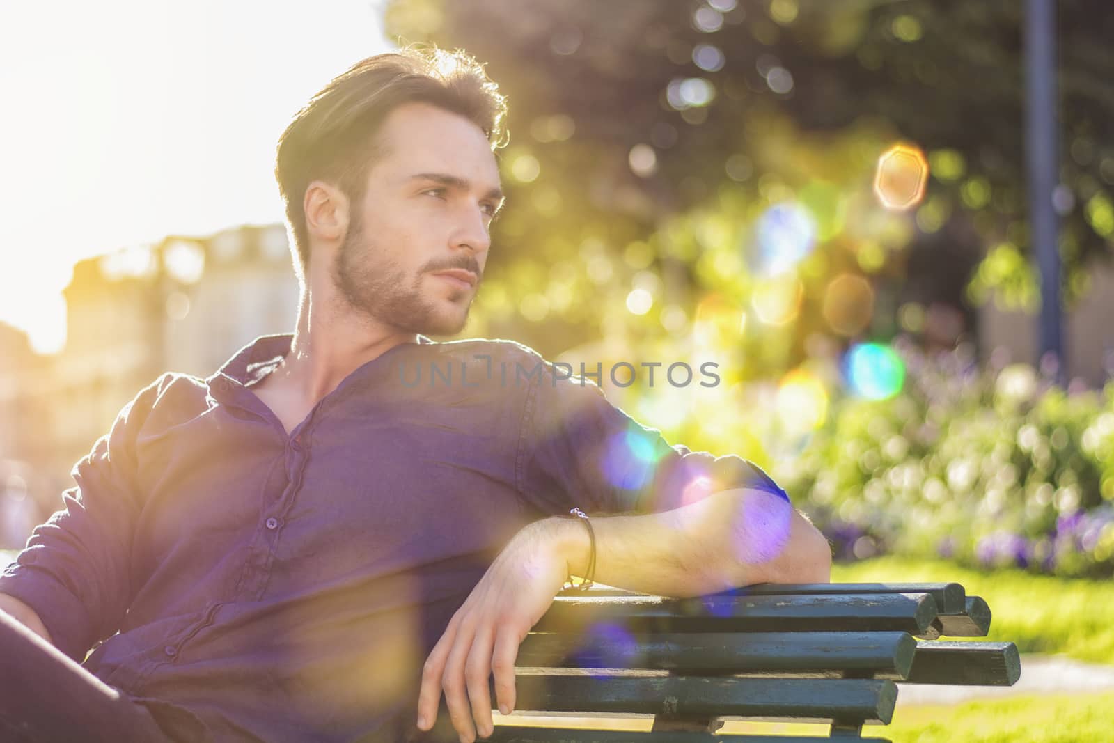 One handsome young man in urban setting in European city, a city park
