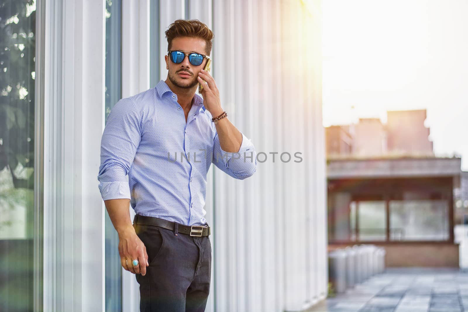 Handsome trendy man talkiing on cell phone by artofphoto