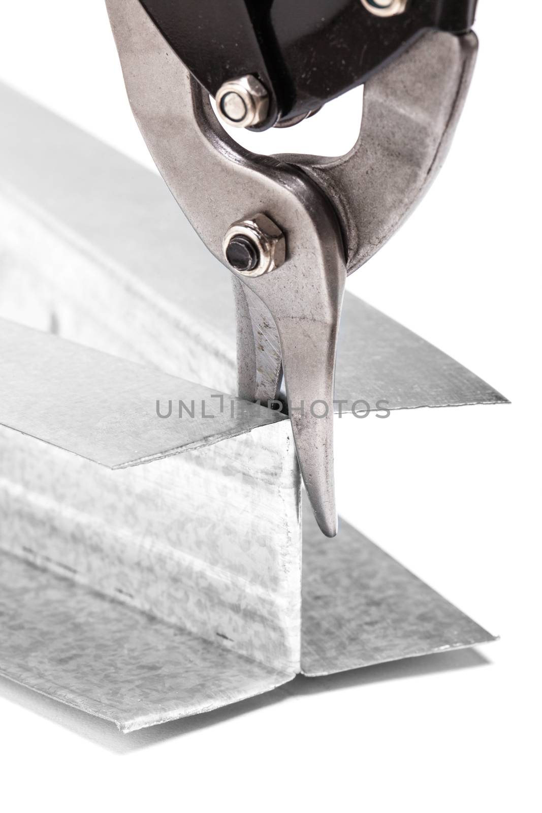 industrial scissors cutting U-shaped metal profile for drywall support isolated on white background