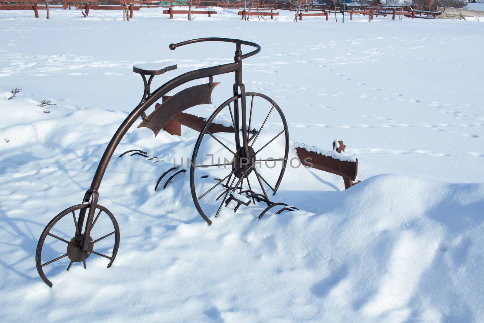Iron sculpture of bicycle in white snow on wintertime