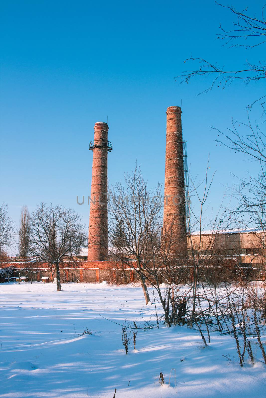 Two factory plant tubes pipes view with winter snowed landscape