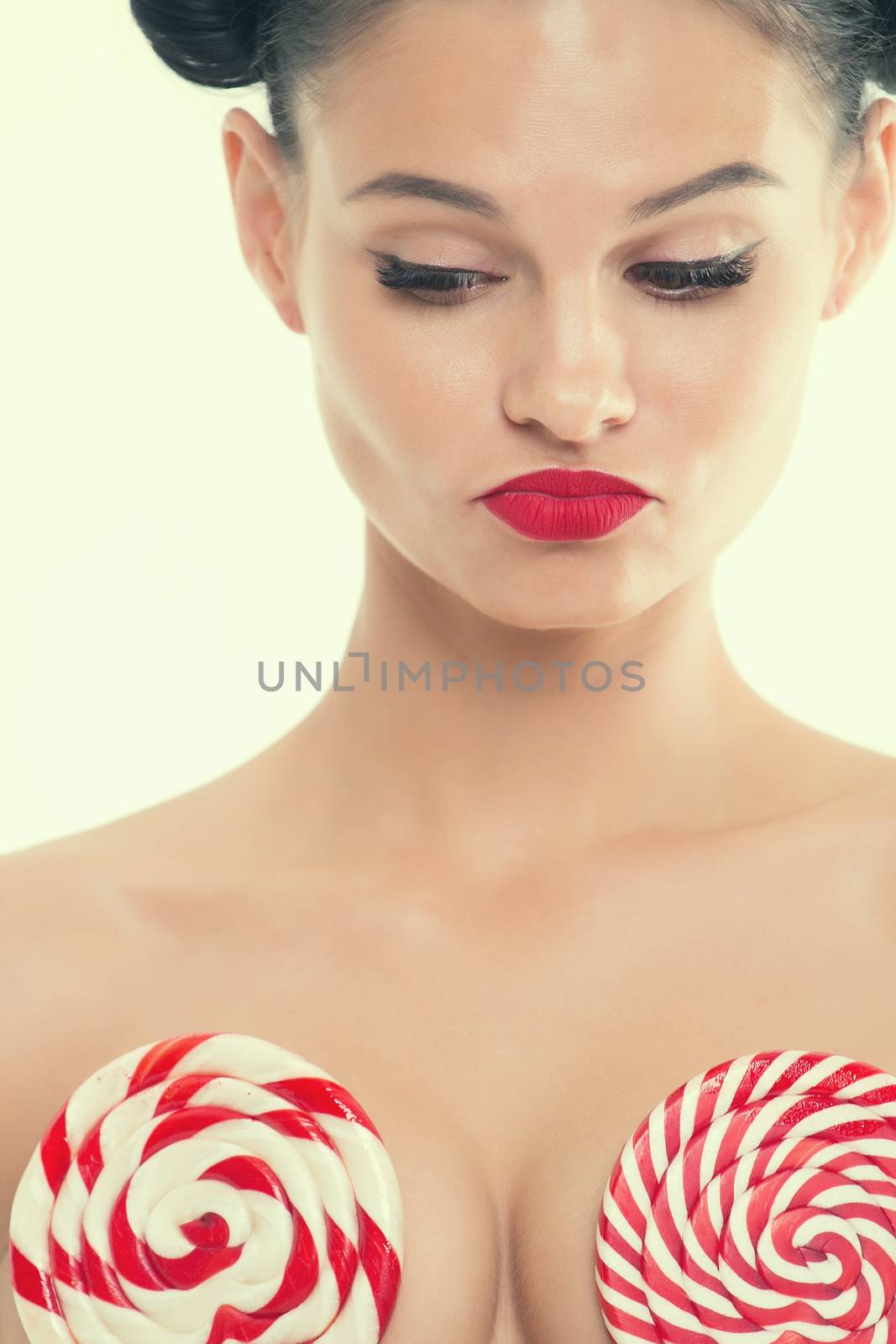 Portrait of a young girl in lingerie with red lipstick and big lollipops which it covers the chest.