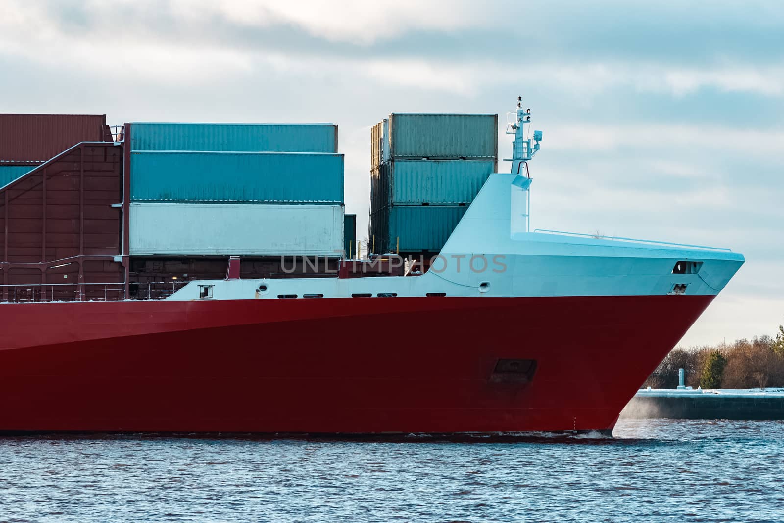 Full red container ship moving in still water