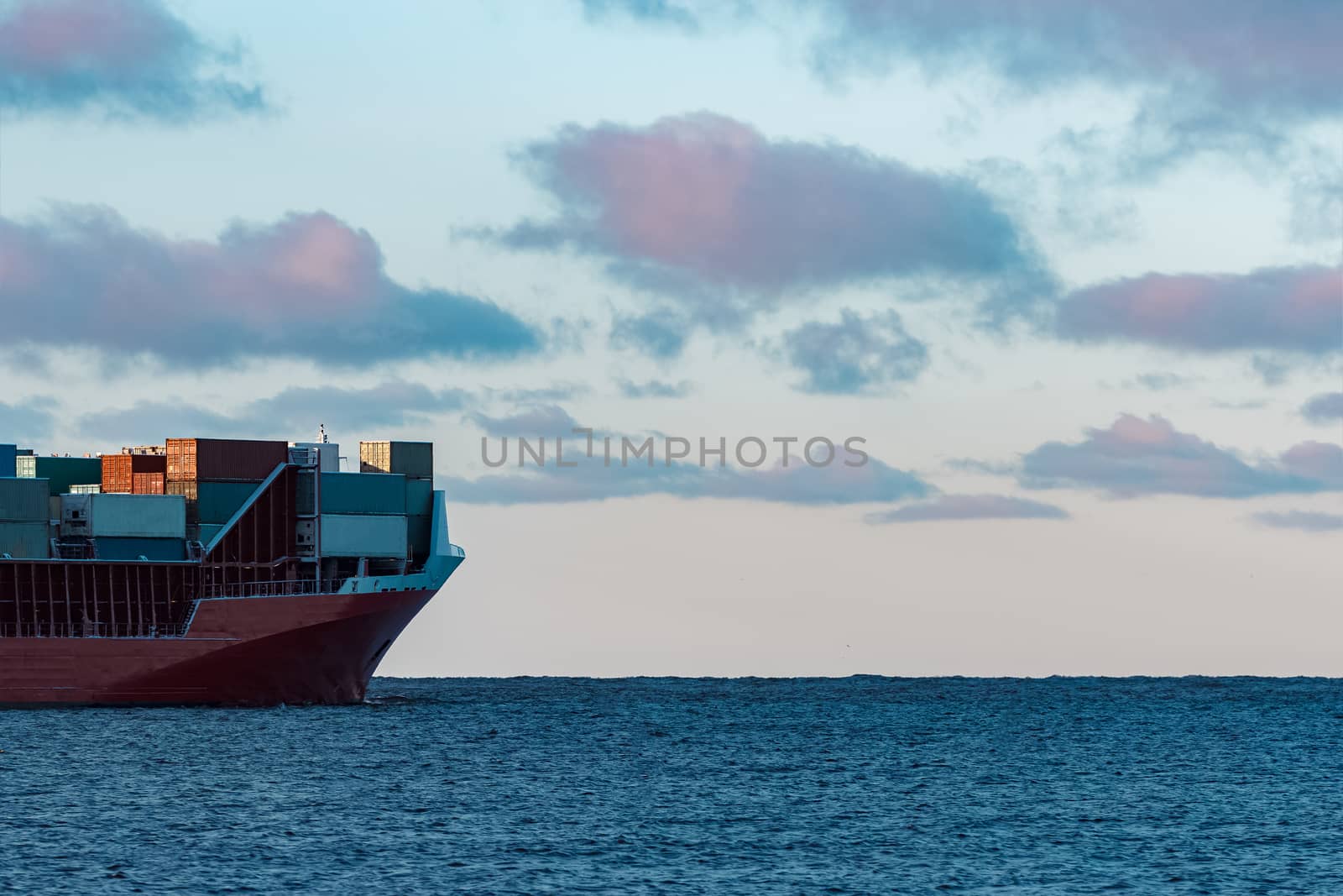 Full red container ship moving in still water