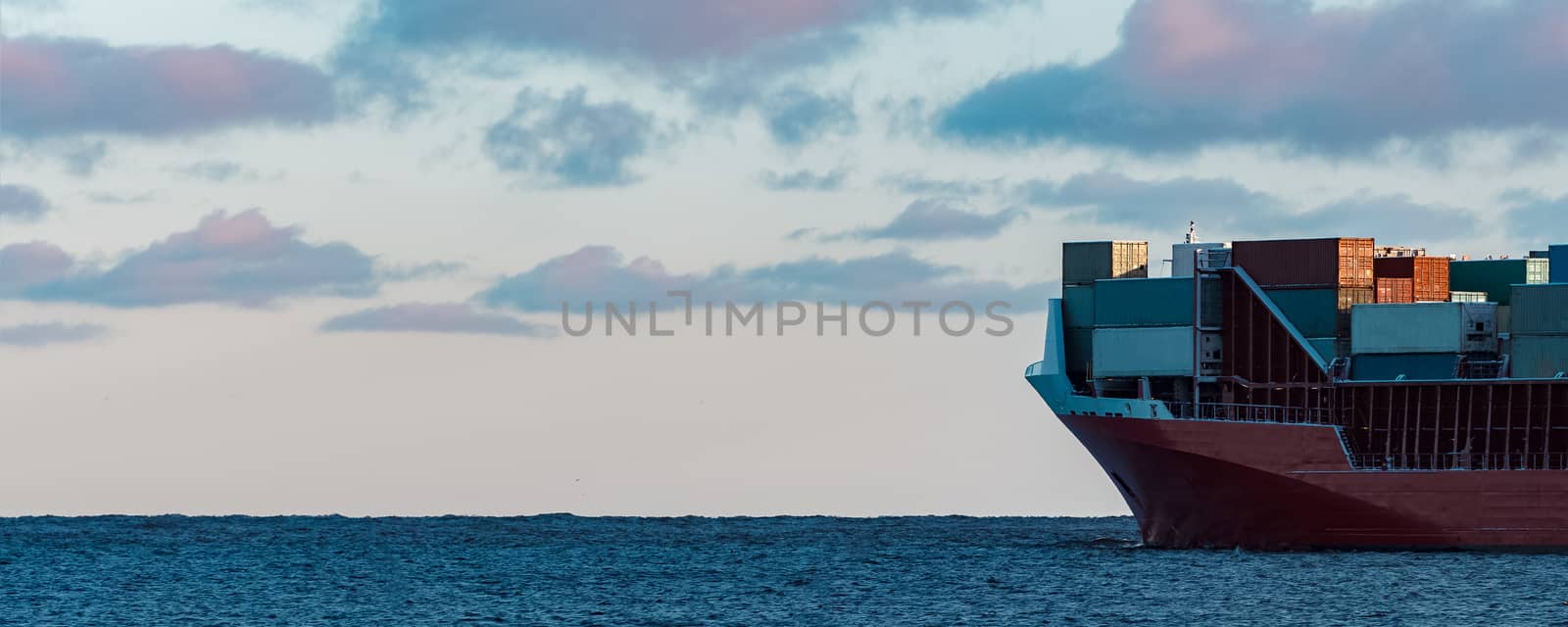 Full red container ship moving in still water