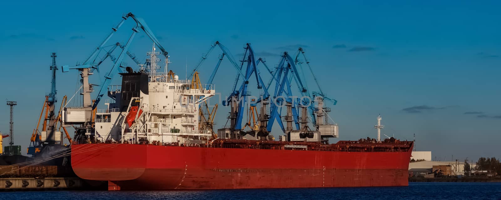 Red cargo ship loading in the port of Riga, Europe