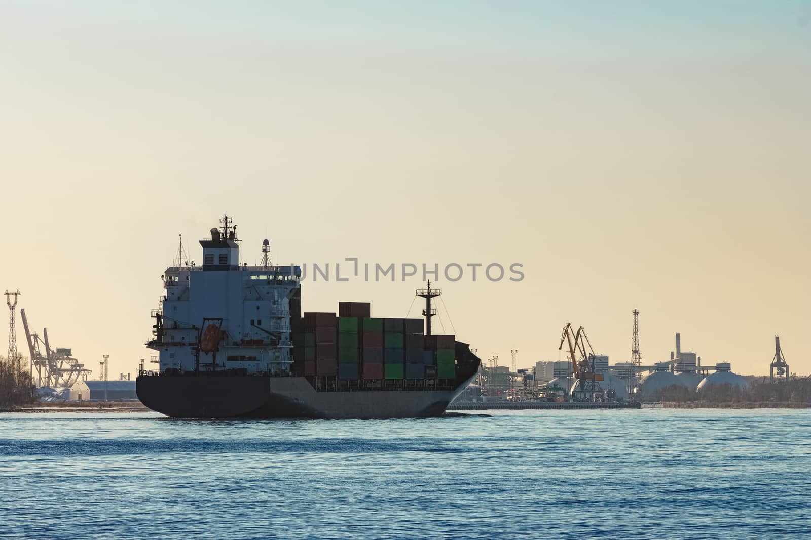 Modern grey container ship moving in still water