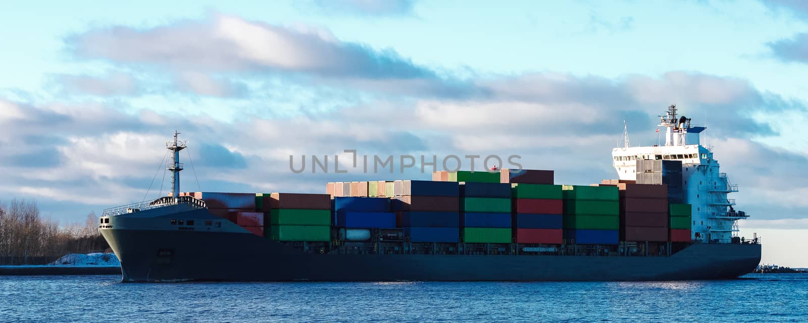 Modern grey container ship moving in still water