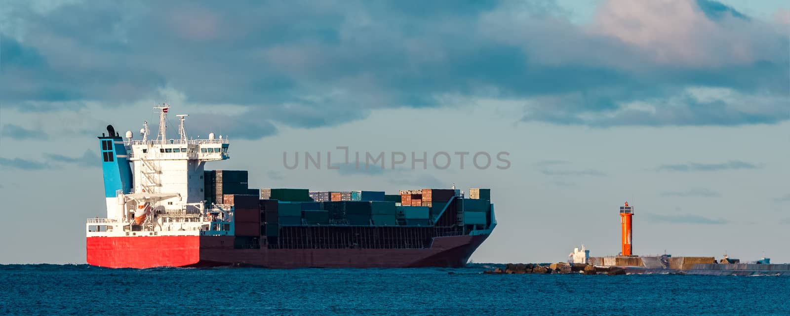 Full red container ship moving in still water