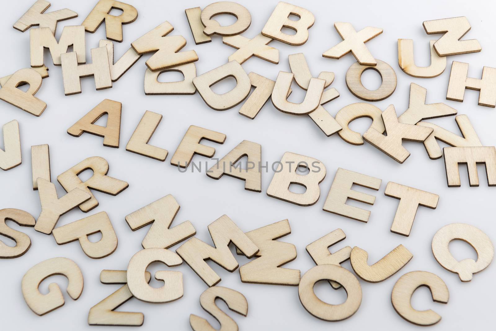 The word alphabet in Dutch translation in wooden letters diagonally placed with loose wooden letters around it.
