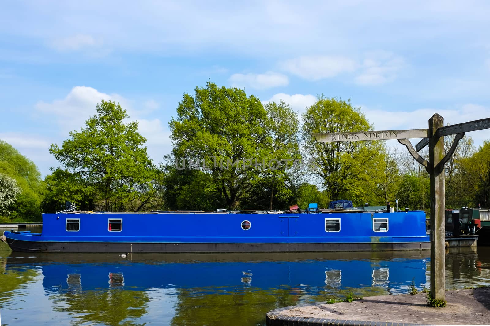 Blue British canal boat parked in a dock at Lapworth, a Warwickshire village.
