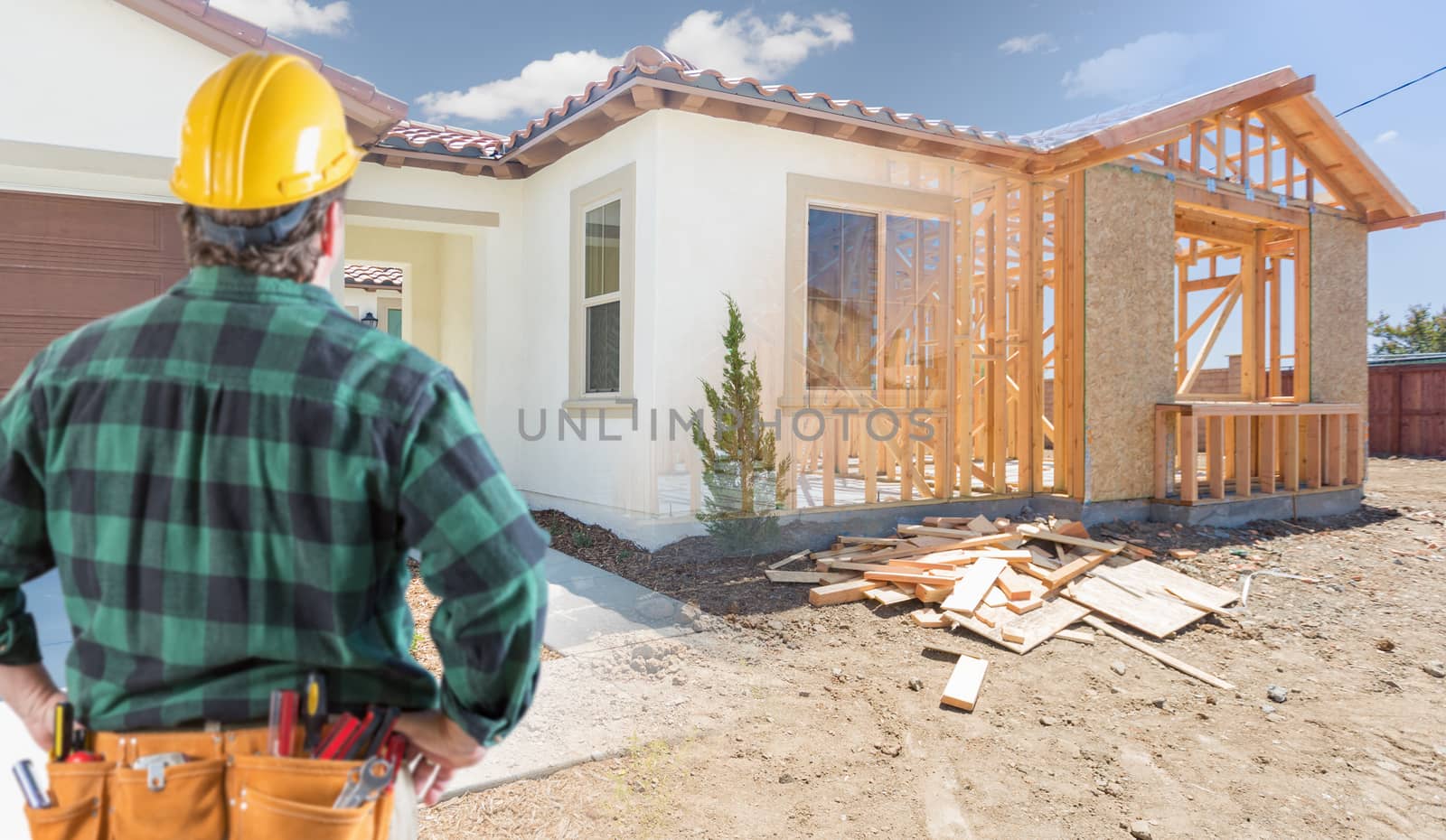 Contractor Standing Outside Construction Framing and Photo of New House.