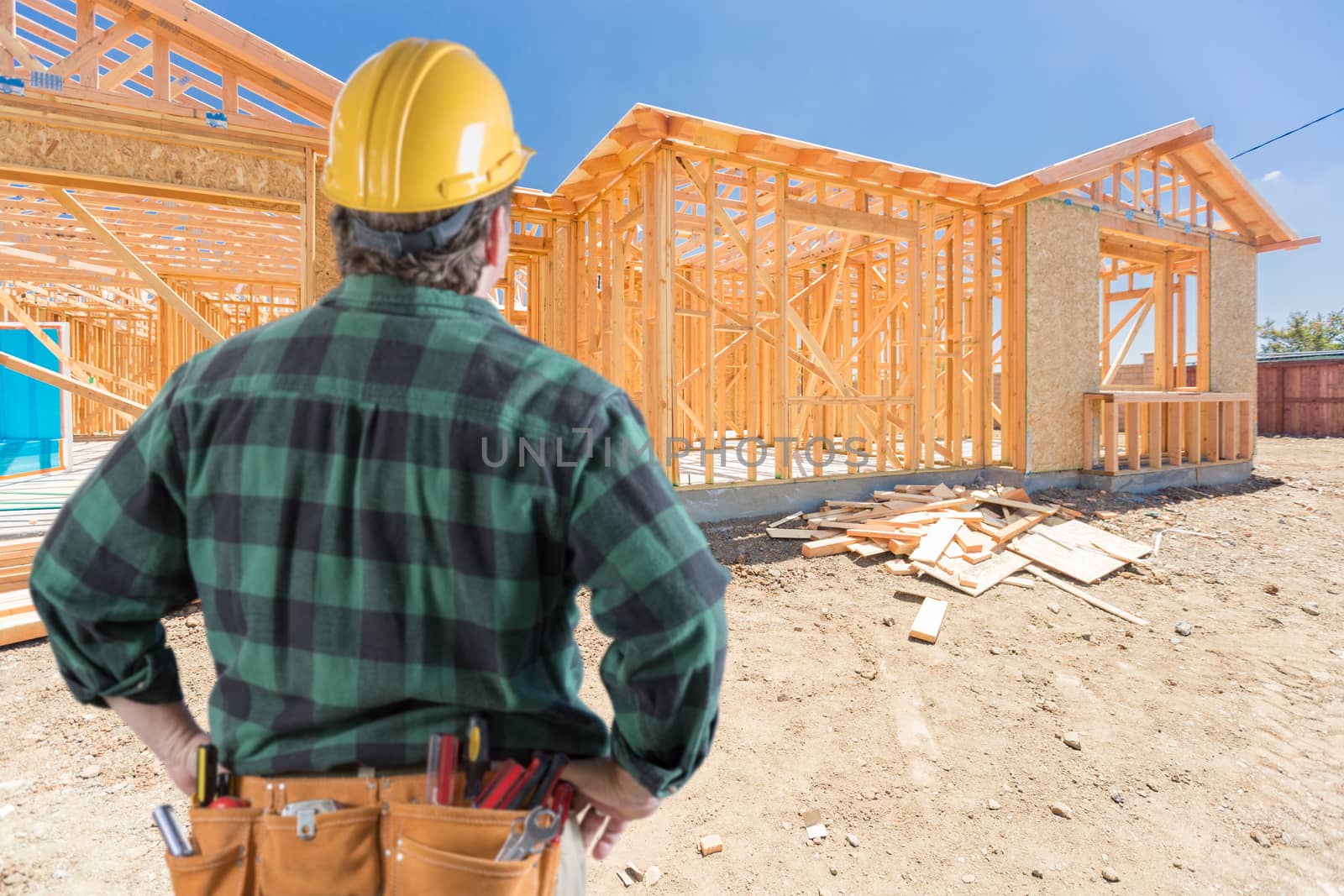 Contractor Standing Outside Construction Framing of New House.