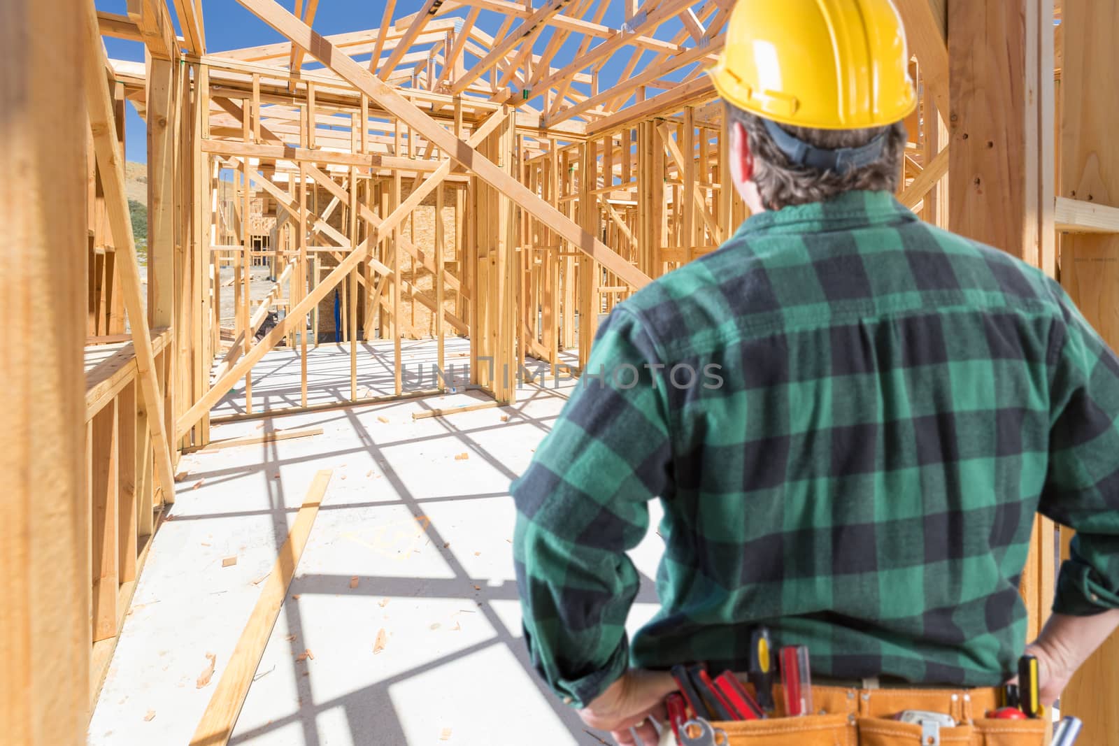 Contractor Standing Inside Construction Framing of New House. by Feverpitched