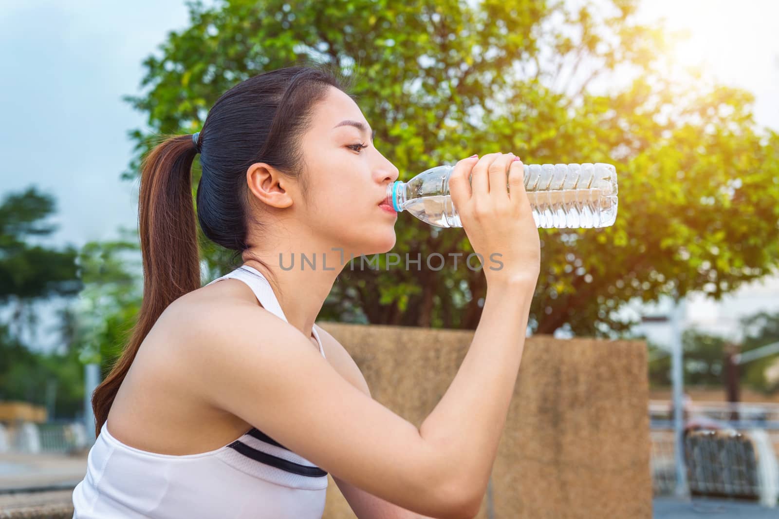 Sporty young woman drinking water after jogging.