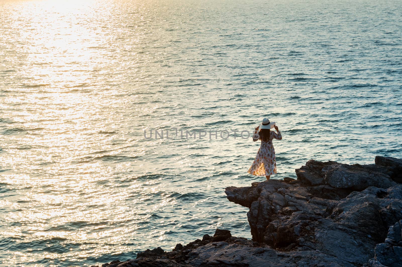 Young woman standing on the top of rock and looking at the seashore and sunset in Si chang island. by gutarphotoghaphy