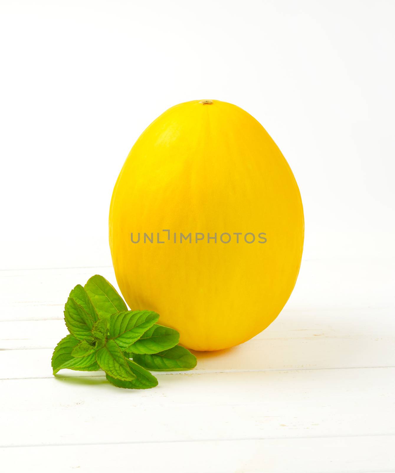 whole yellow melon on white wooden background