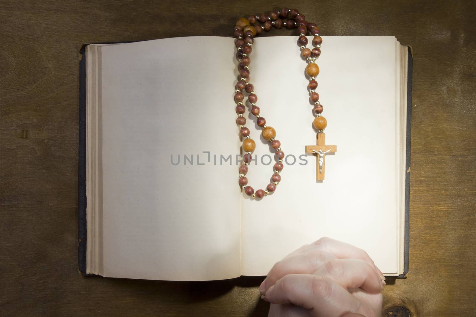 Female hands with rosary and an old book