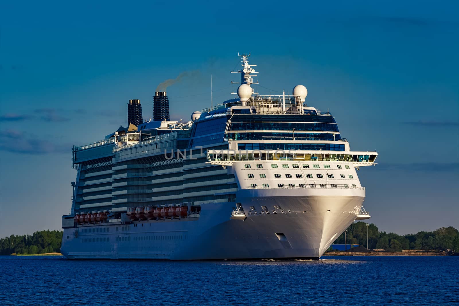 Giant white passenger ship moving past the port on a clear day