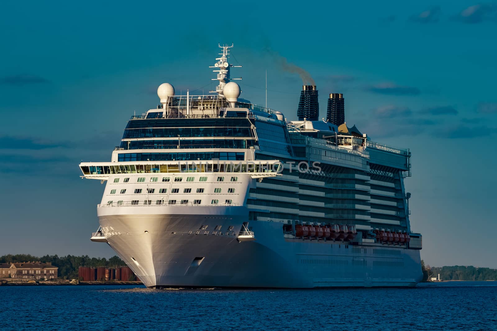 Giant white passenger ship moving past the port on a clear day