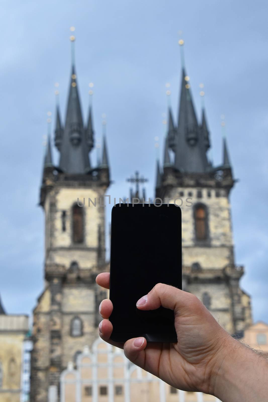 Close up man hands with smartphone taking picture of old town cityscape with Cathedral of Our Lady before Tyn, Prague, Czech Republic