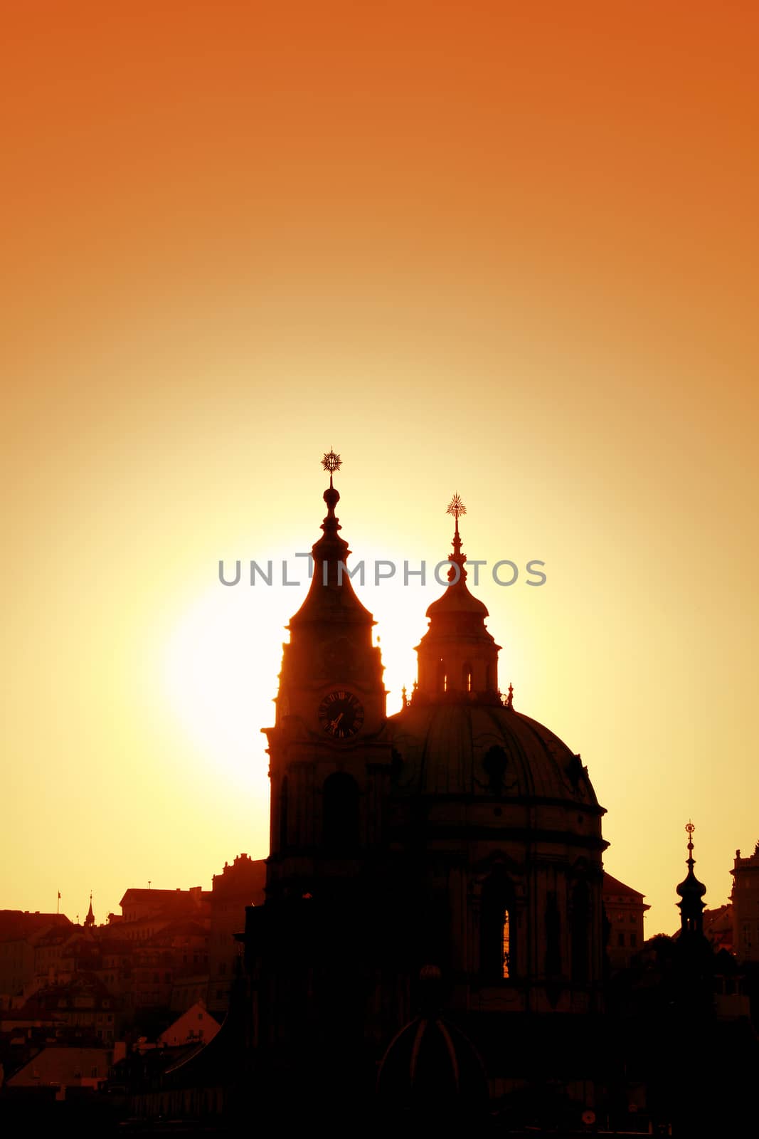 Sunset backlit silhouettes of Saint Nicholas Church and roofs of cityscape skyline of lesser old town in Prague, Czech Republic