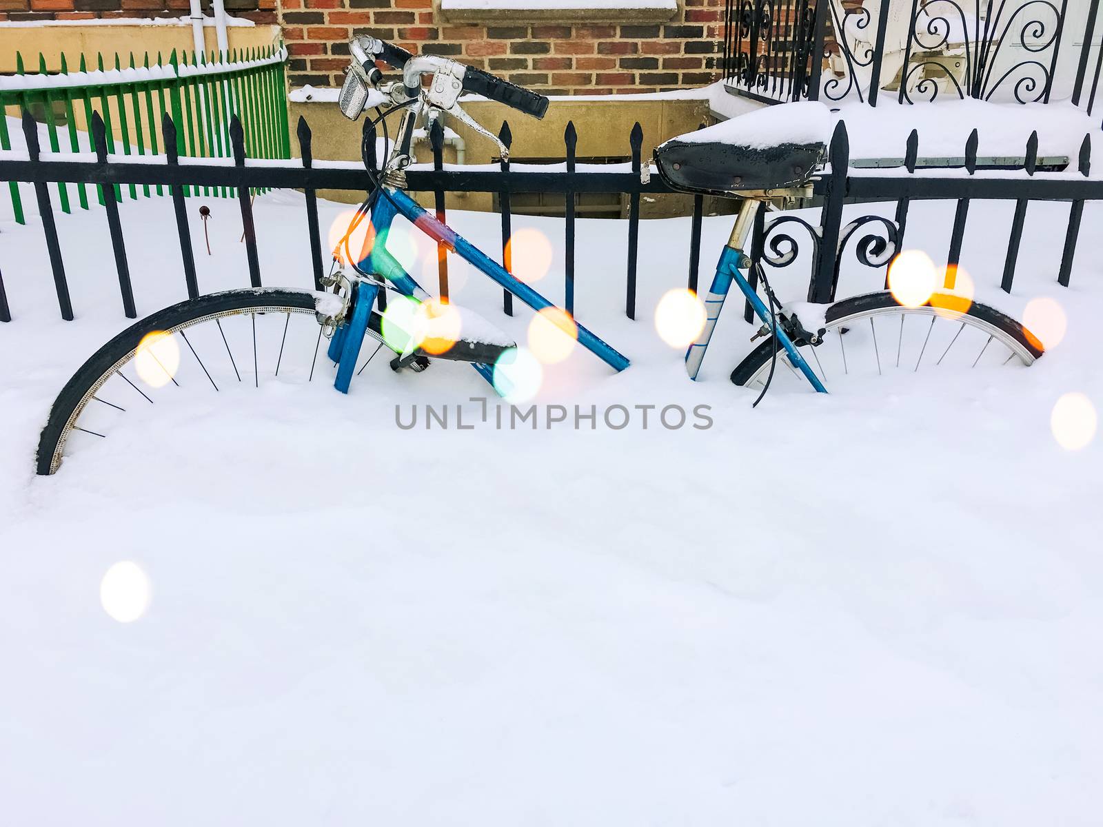 Bicycle in snow, after snowstorm, near an urban building. Bokeh light effect.