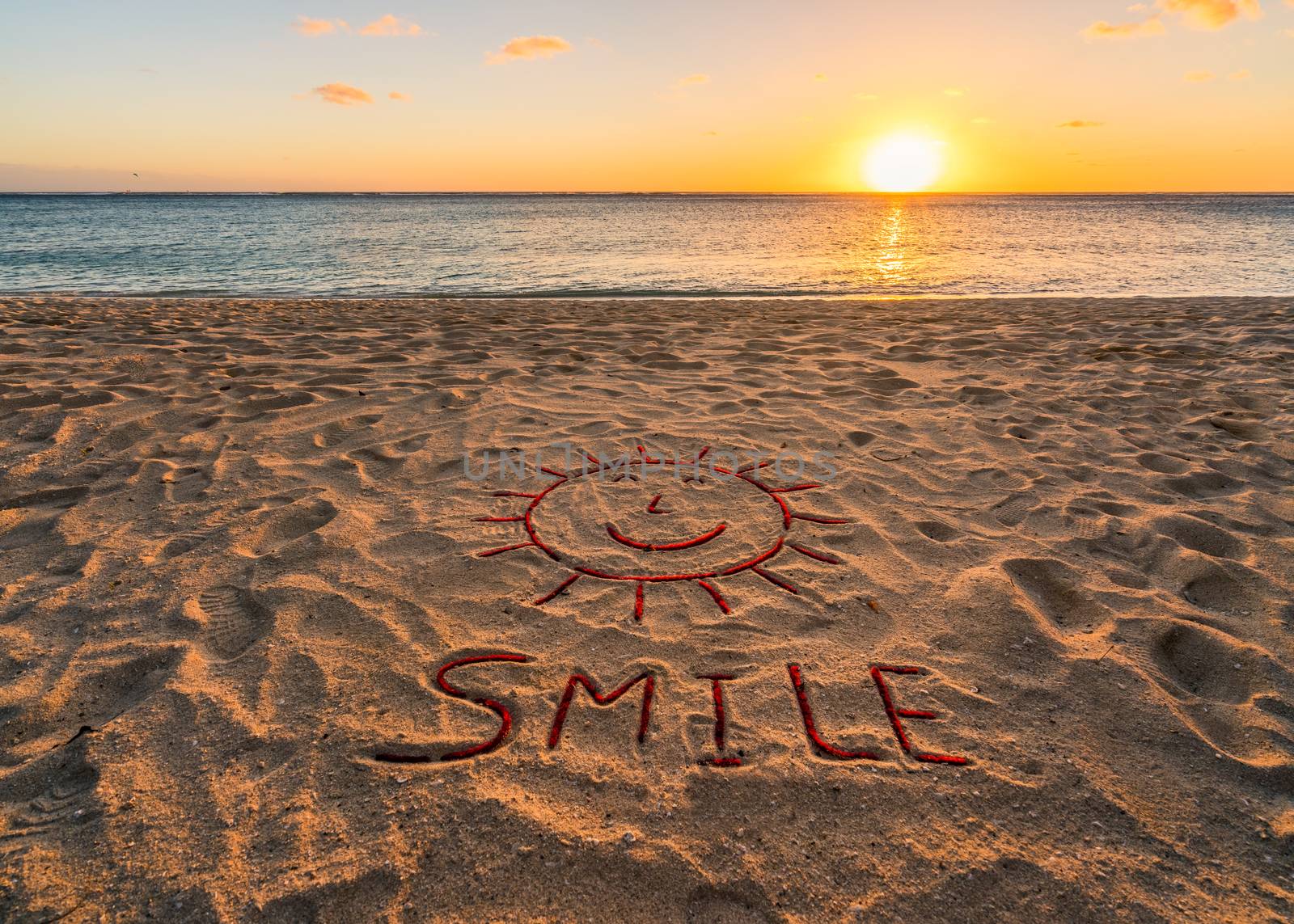 Handwritten on the sand "Smile".Beautiful sand beach at sunset.