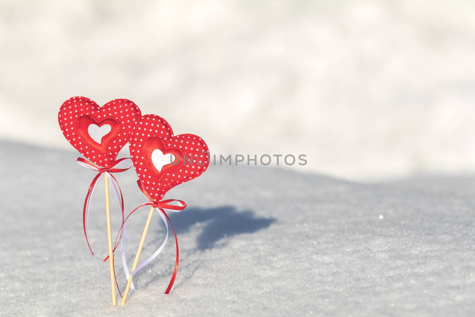 Beautiful valentine holiday background with two checkered hearts on cane, white snow surface.