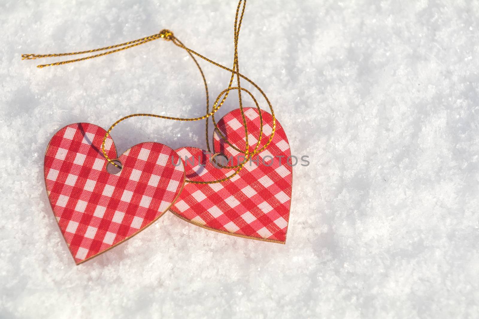 Beautiful valentine holiday background with two checkered motley hearts on white snow surface.