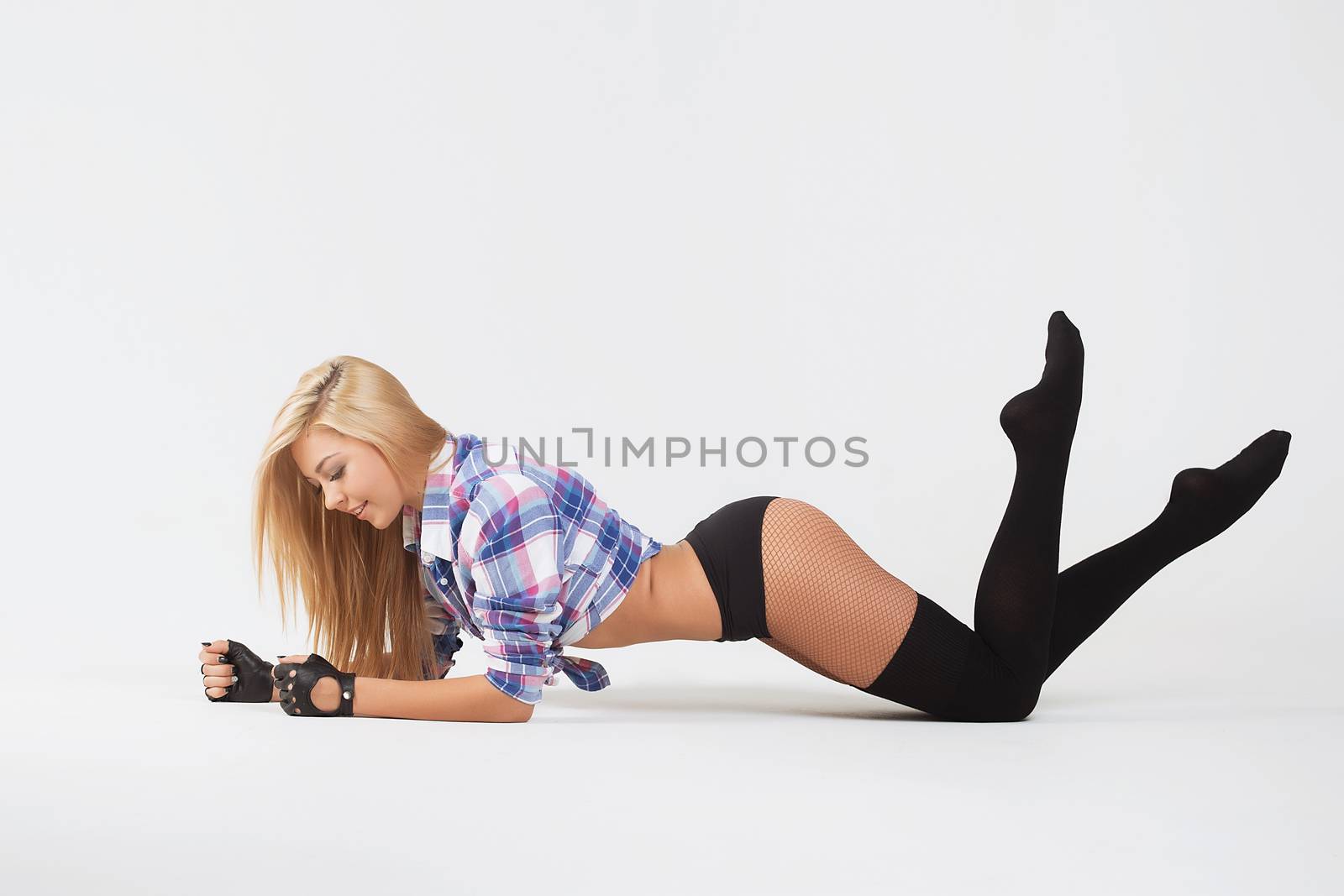 Blonde girl in stockings lying on the floor on white background.