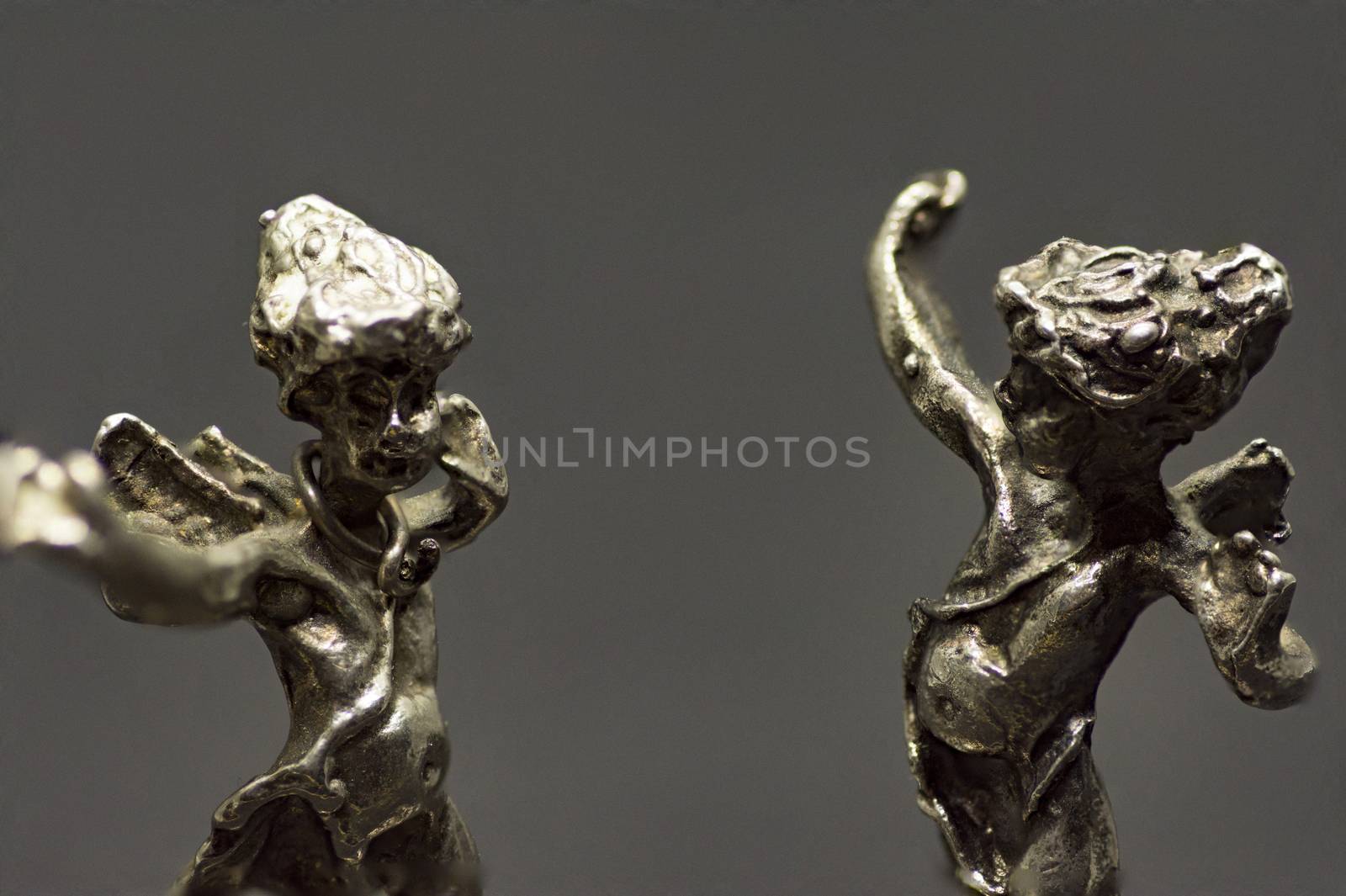 two metallic figurine angels are dancing