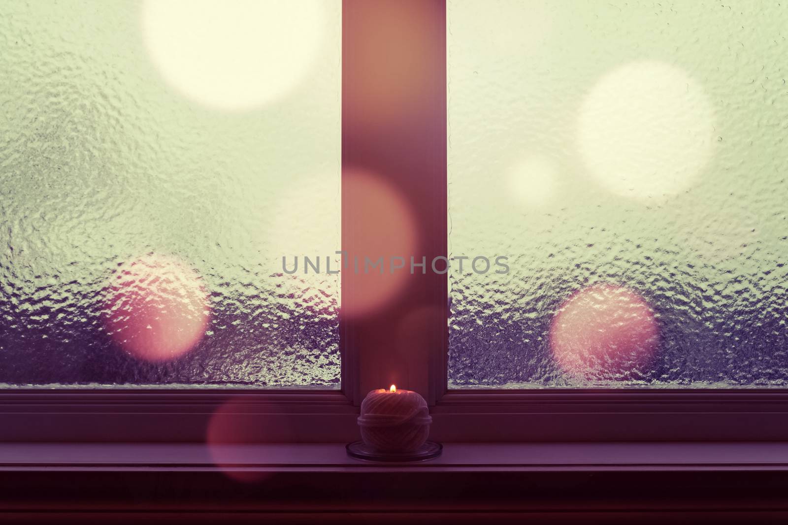 Winter window with burning candle and bokeh lights by anikasalsera