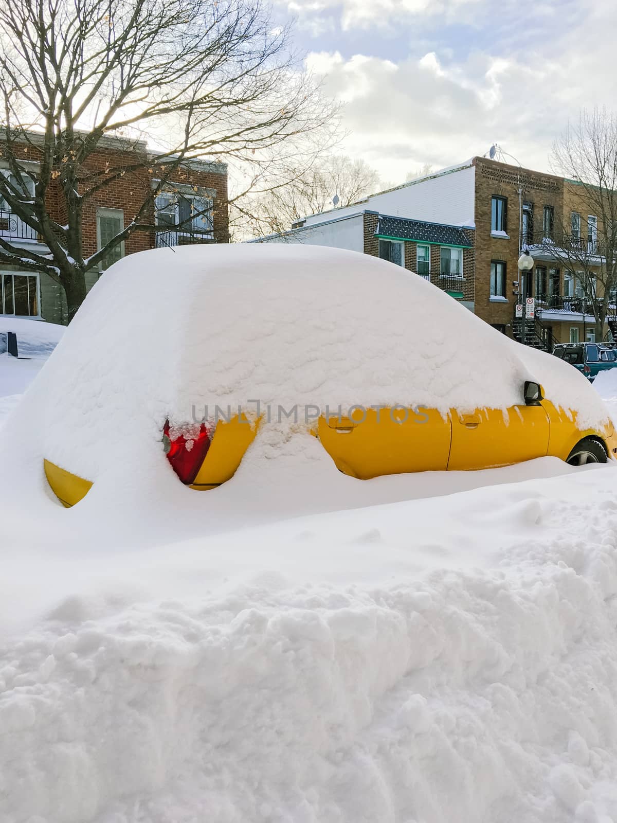 Urban street with a yellow car stuck in snow by anikasalsera