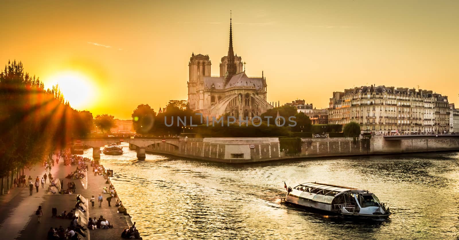 Sunset over Paris wharf and Notre-dame in summer with a peniche boat passing by