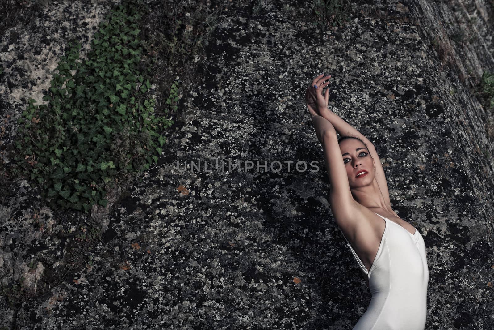 portrait of a beautiful young ballerina posing in front of a big wall of an old castle