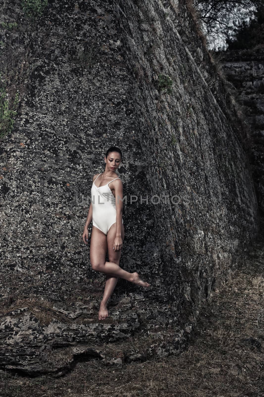 portrait of a beautiful young ballerina posing in front of a big wall of an old castle