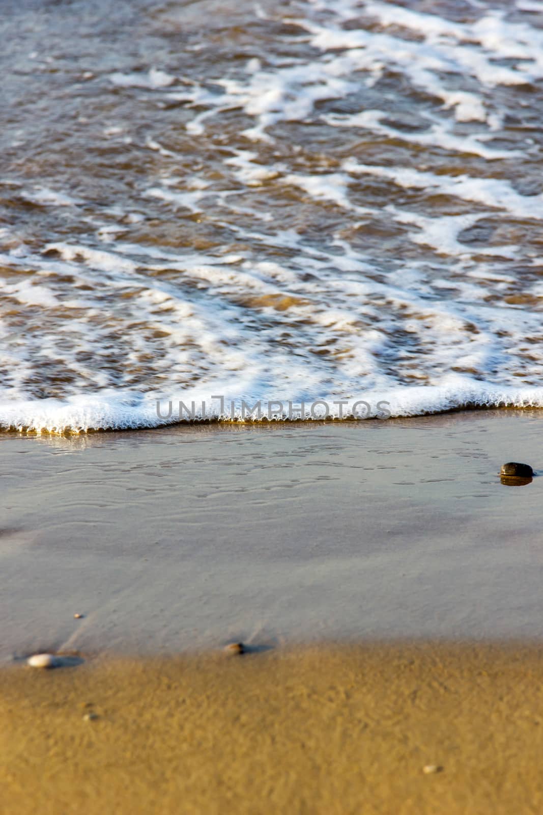 close up of small waves at the edge of the beach 