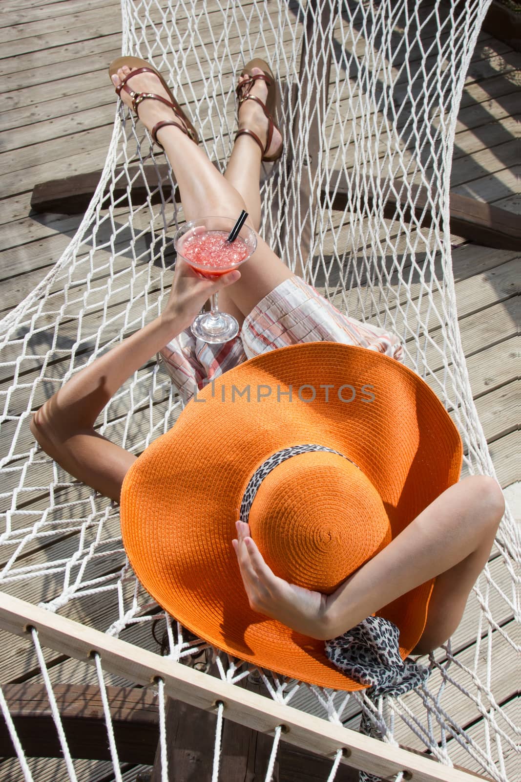 beautiful young girl relaxing on a hammock with a cocktail