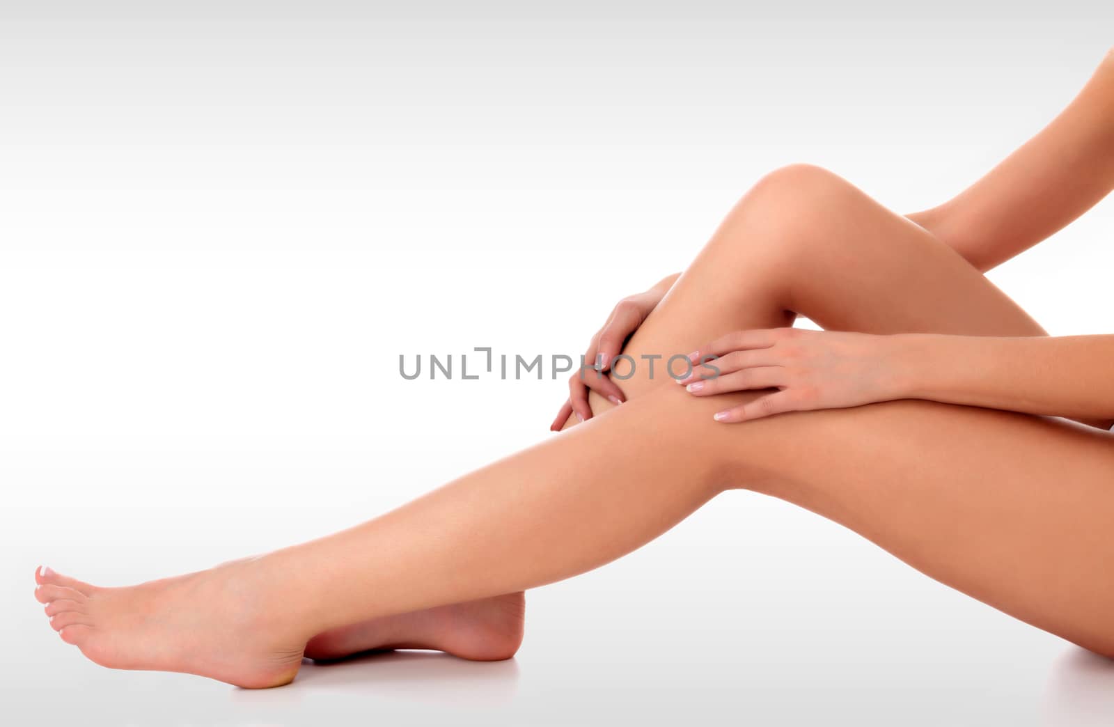 Closeup shot of beautiful female legs and hands on light grey backround. Unwanted hair removal concept