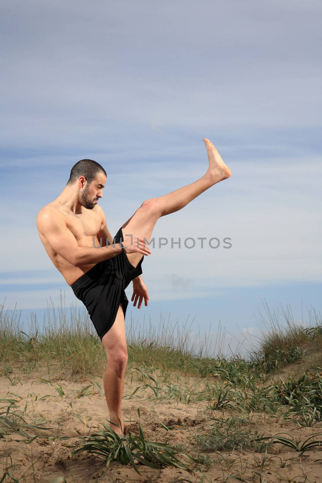 young martial arts instructor exercising on a sand hill